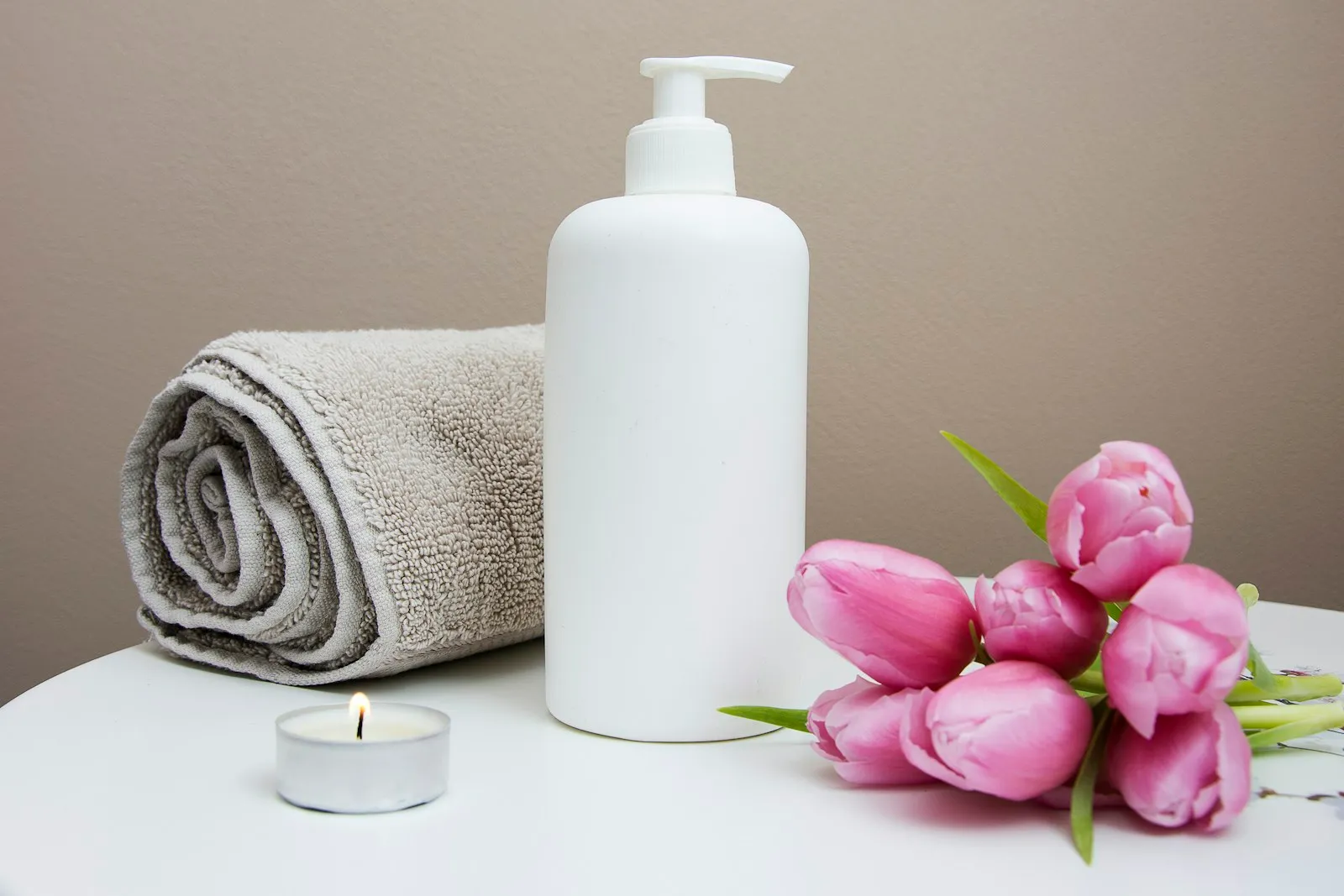 Soft, inviting room set up for a calming home massage with candles and towels
