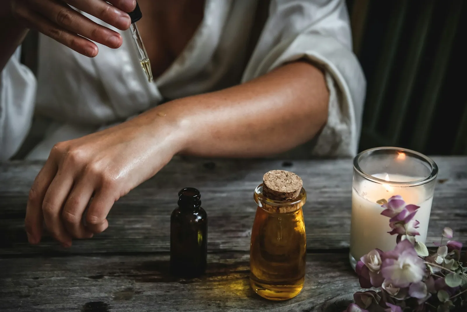 Warm massage oils and a lit candle arranged for a calming therapy session